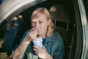 girl eating ice cream with a spoon in the car. blond girl in a raincoat, eats ice cream while in the car during a road trip