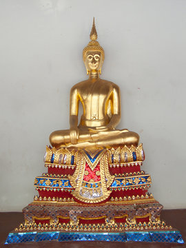 Single Buddha image against white wall.