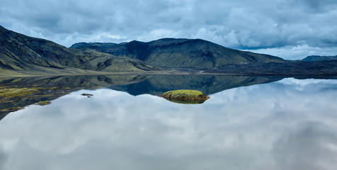 Lake coast with mountain reflection at the cloudy day, Iceland