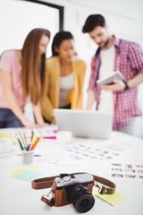 Close-up of camera on desk with editors working