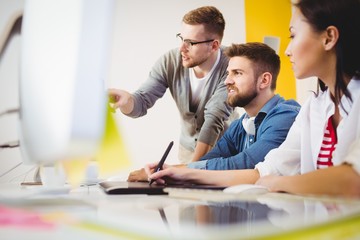 Executive pointing at computer to colleagues 