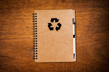 Notebook paper with pen on wooden background.