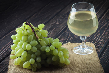 Green fresh ripe grapes and a glass of white wine