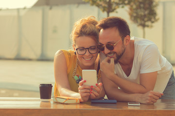Couple using cellphone outdoors.


