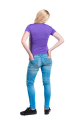 Fototapeta premium back view of standing young beautiful woman. girl watching. Rear view people collection. backside view of person. Long-haired blonde in the purple shirt stands with his hands back pockets of his