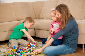 Naklejka premium Children and their mother are playing with blocks on the ground