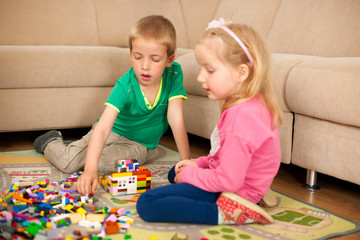 Children and their mother are playing with blocks on the ground