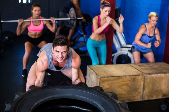 Portrait Of Smiling Man Lifting Tire In Gym