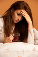 illness flu - ill woman drink tea in bed