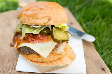 large burger on wooden board with knife and fork