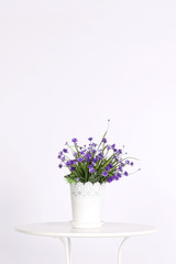 White pot with artificial flowers on table on light background