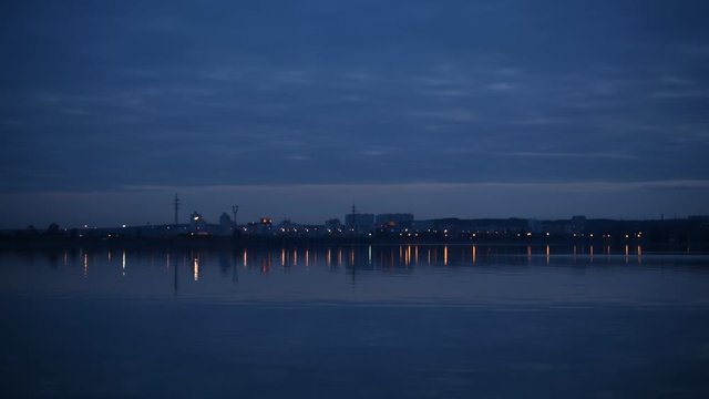 Urban landscape with city lights reflected in water in the evening with many transmission towers. Shot in Ukraine on Dnieper river near Kiev