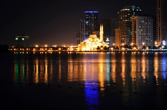 Colorful dancing fountain with mosque in the city at night with lively music, Sharjah, United Arab Emirates