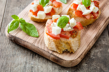 Caprese salad bruschetta with tomatoes,mozzarella and basil on wooden table

