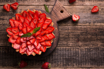 Tart with strawberries and whipped cream on wooden vintage table