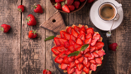 Tart with strawberries and whipped cream on wooden vintage table