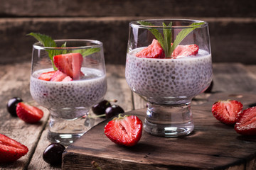chia seed pudding with strawberries and min on wooden vintage background