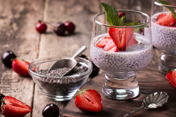chia seed pudding with strawberries and min on wooden vintage background