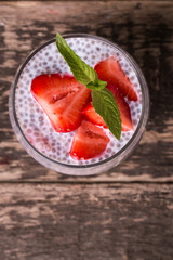 chia seed pudding with strawberries and min on wooden vintage background