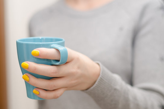 Woman keeping a blue  cup of tea