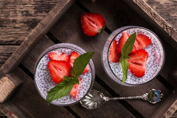 chia seed pudding with strawberries and min on wooden vintage background