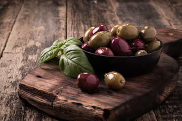 Olives on wooden dark table with basil