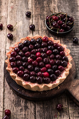 Tart with cherry and whipped cream on wooden vintage table