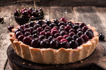 Tart with cherry and whipped cream on wooden vintage table