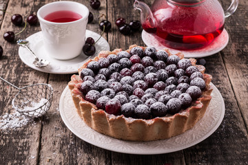 Tart with cherry and whipped cream on wooden vintage table