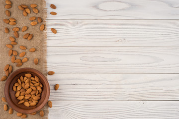 Almonds in a brown bowl and old white wooden table.