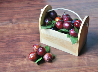 Plums with leaves in wooden box. Свежие сливы в деревянном ящике для фруктов.