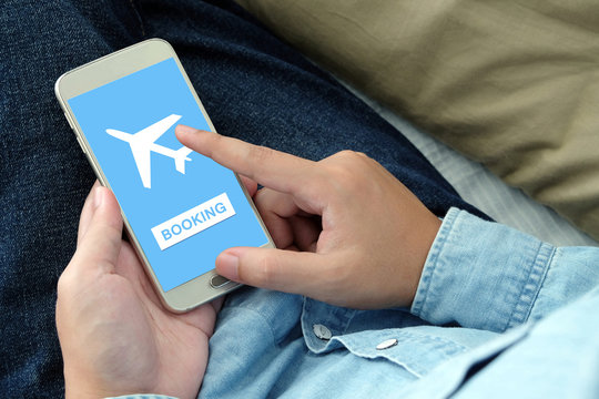 Hand holding phone with airline tickets booking on screen - Powered by Adobe