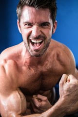 Fototapeta premium Portrait of cheerful shirtless athlete flexing muscles 