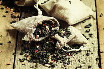 Dry green tea with flower petals in canvas bags, vintage wood ba