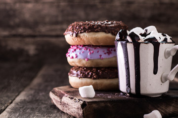 donuts and a cup of coffee with chocolate on a wooden table