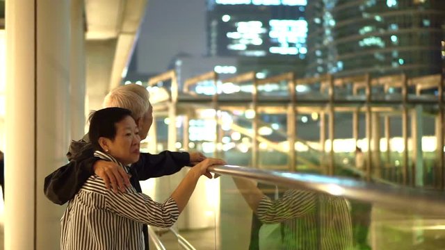 Asian senior couple looking at apartment in modern business district for investment and retirement