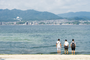 海岸に佇む3人の男性の後ろ姿
