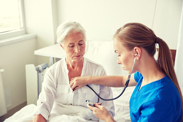 nurse with stethoscope and senior woman at clinic