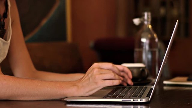 Woman works on a laptop in a cafe