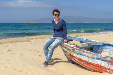 Young woman on stylish outfit sitting on an abandoned fishing bo