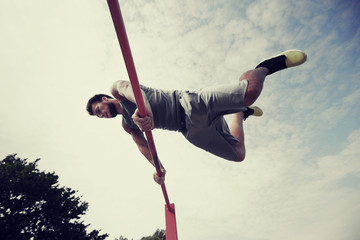 young man exercising on horizontal bar outdoors
