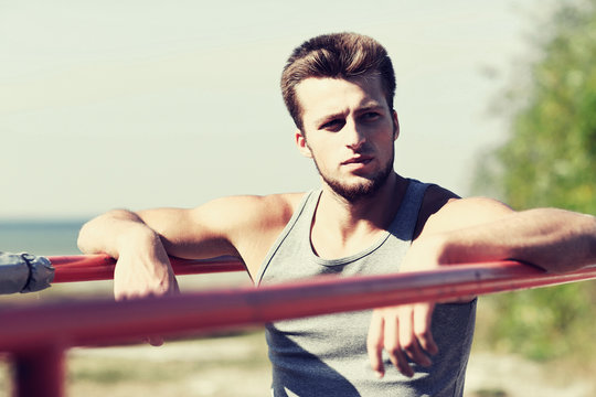 young man exercising on parallel bars outdoors
