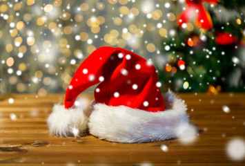 close up of santa hat on wooden table over lights