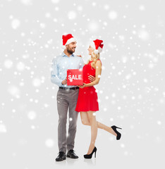 Obraz premium happy couple with red sale sign over snow