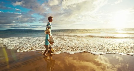 Father and son walking on the beach at sunset