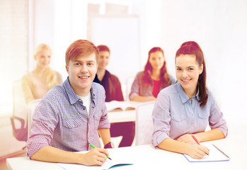 Fototapeta premium smiling students with notebooks at school