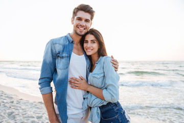 Happy young couple standing and hugging on the beach