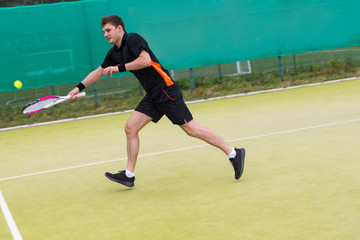 Young man playing tennis on tennis grass court  at early morning