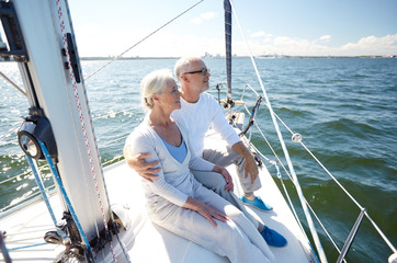 senior couple hugging on sail boat or yacht in sea