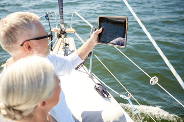 senior couple with tablet pc on sail boat or yacht